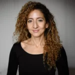 Headshot of Iman Kerroua, associate teaching artist for Physical Lab, wearing a long-sleeve black shirt
