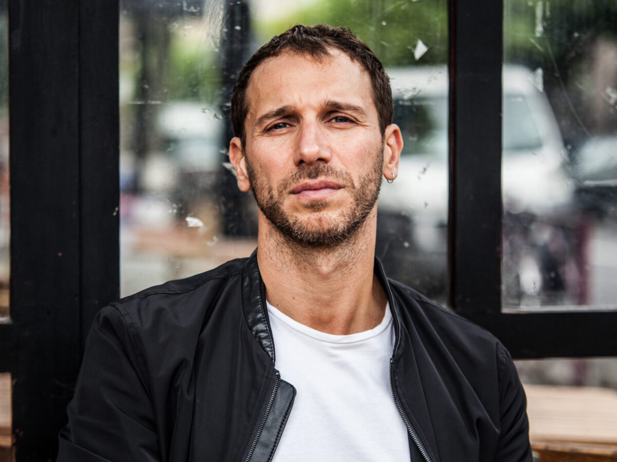 Headshot of Yorgos Karamalegos, Physical Lab founder, wearing a white t-shirt and black leather jacket