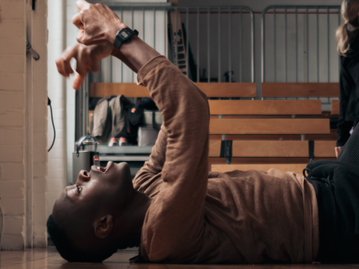 Man lying on hardwood floor of studio, fists held above him in frustration.